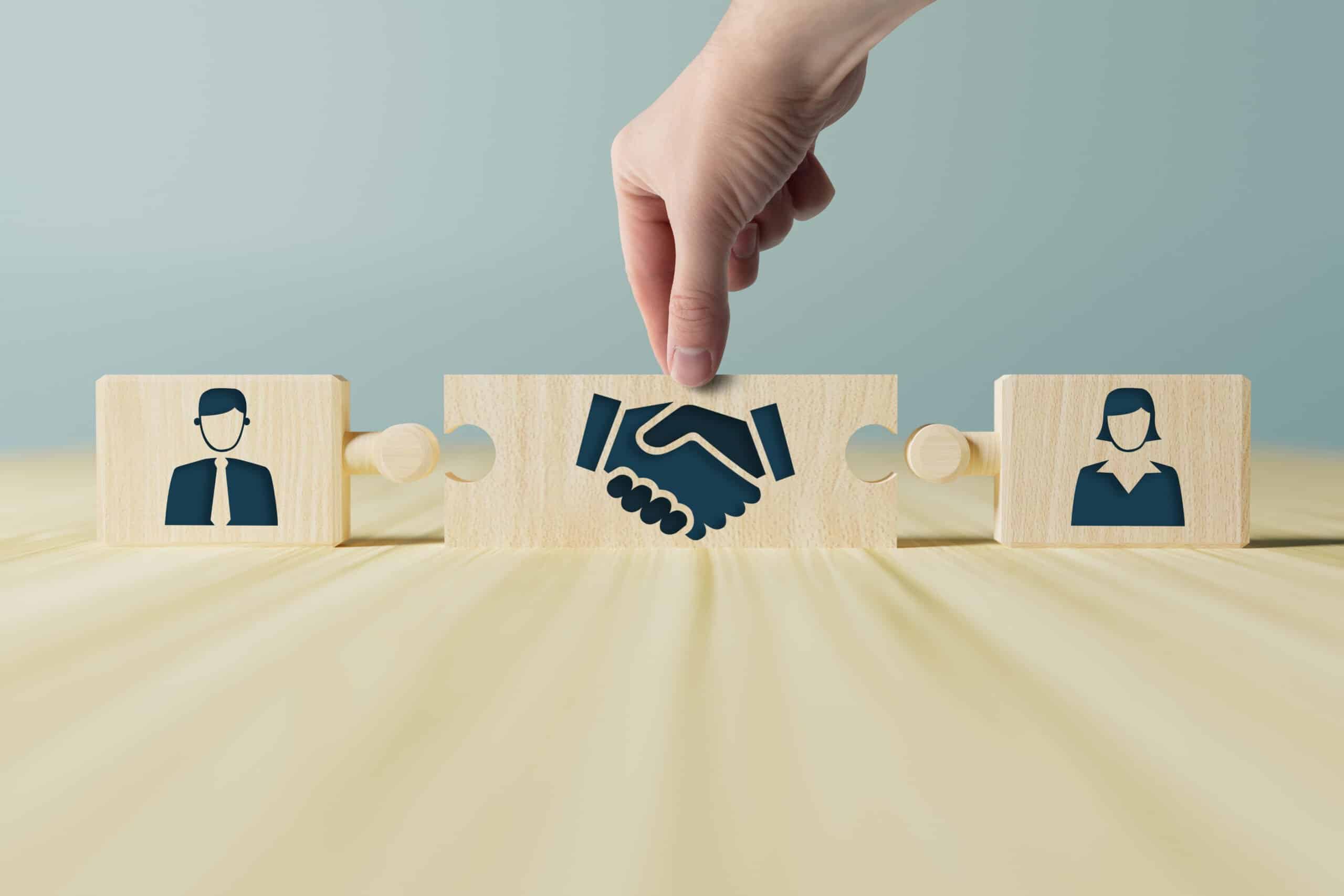 The hand holds wooden wooden blocks with icons of a woman and a